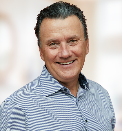 Man smiling in blue striped shirt with blurred background