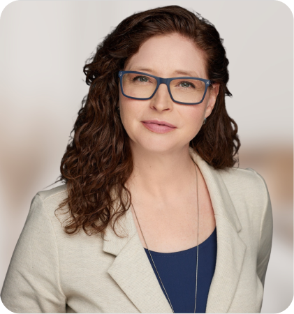Portrait of a woman with curly hair and glasses wearing a cream blazer